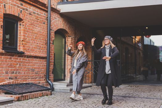 Young pretty girls friends having fun outdoor in autumn evening in city laughing and going crazy on the street - friendship and funny people