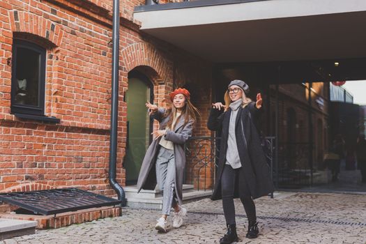 Young pretty girls friends having fun outdoor in autumn evening in city laughing and going crazy on the street - friendship and funny people