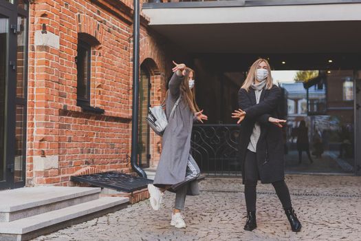 Young pretty girls friends having fun outdoor in autumn evening in city laughing and going crazy on the street - friendship and funny people