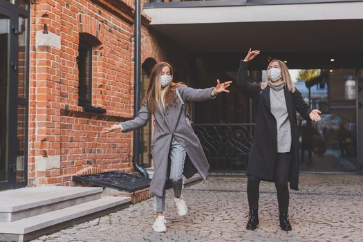 Young pretty girls friends having fun outdoor in autumn evening in city laughing and going crazy on the street - friendship and funny people