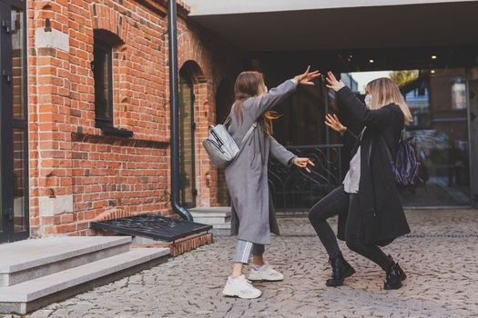 Young pretty girls friends having fun outdoor in autumn evening in city laughing and going crazy on the street - friendship and funny people