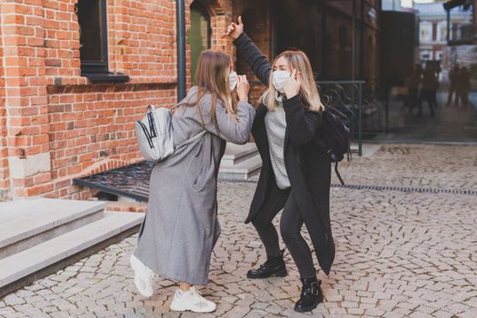 Young pretty girls friends having fun outdoor in autumn evening in city laughing and going crazy on the street - friendship and funny people