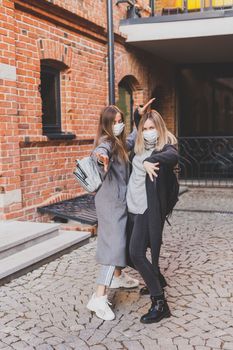 Young pretty girls friends having fun outdoor in autumn evening in city laughing and going crazy on the street - friendship and funny people