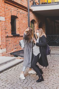 Young pretty girls friends having fun outdoor in autumn evening in city laughing and going crazy on the street - friendship and funny people