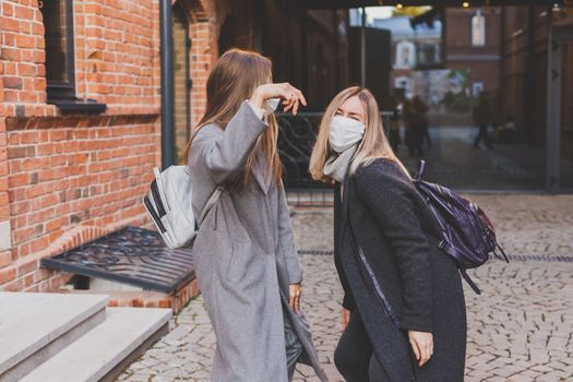 Young pretty girls friends having fun outdoor in autumn evening in city laughing and going crazy on the street - friendship and funny people