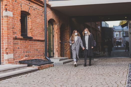 Young pretty girls friends having fun outdoor in autumn evening in city laughing and going crazy on the street - friendship and funny people