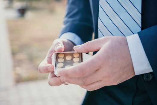 Man takes and shows pills vitamins or drugs tablets in hand from pill bottle, macro shot