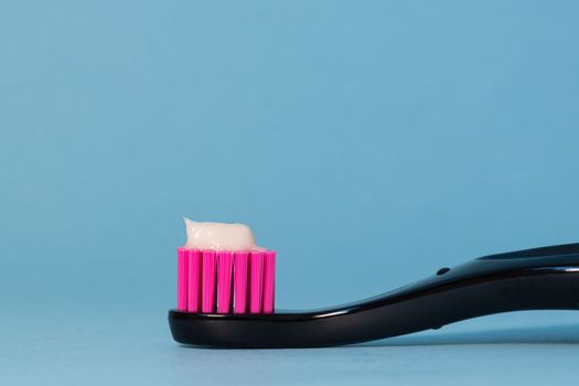 Close up toothbrush neon pink color with toothpaste on blue background. Dentists day concept. Toothbrush day copy space