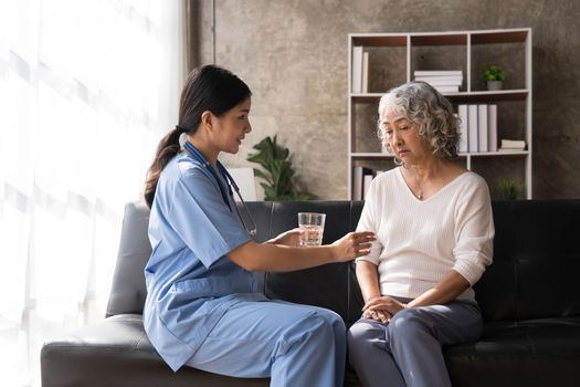 Healthcare worker or nurse caregiver giving pills, showing a prescription drug to senior woman. Elderly healthcare concept..