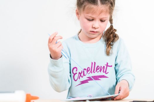 Little girl learning how to sew with sewing craft kit for kids.