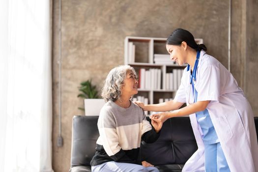 Young caregiver helping senior woman walking. Nurse assisting her old woman patient at nursing home. Senior woman with walking stick being helped by nurse at home...