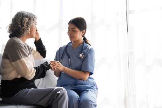 Young caregiver helping senior woman walking. Nurse assisting her old woman patient at nursing home. Senior woman with walking stick being helped by nurse at home...