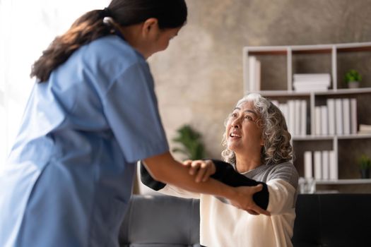 Young caregiver helping senior woman walking. Nurse assisting her old woman patient at nursing home. Senior woman with walking stick being helped by nurse at home...