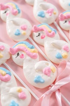 Gourmet unicorn theme meringue pops on a pink background.