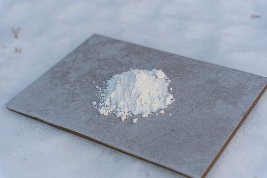 A white chemical powder is poured on a ceramic tile. chemical experiment with urotropin and calcium gluconate. Chemical experiments