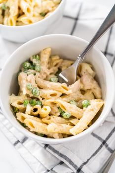 Serving macaroni salad with chicken in white ceramic bowls.