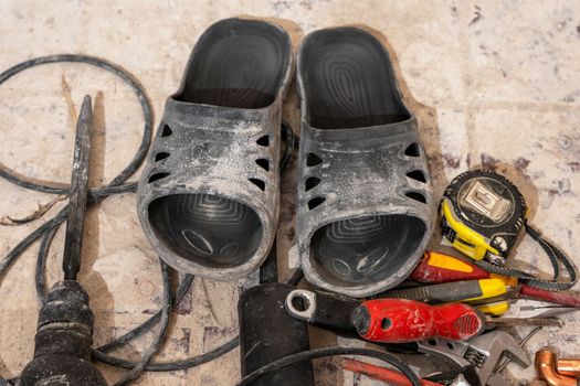 flip-flops and working tool for apartment renovation. A puncher, a grinder and a tape measure.