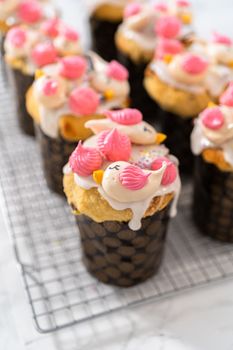 Decorating mini Easter bread kulich with sprinkles and meringue bird-shaped cookies.