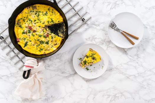 Flat lay. Freshly baked spinach and ham frittata in cast iron skillet.