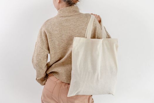 Girl holding cotton linen eco bag mockup, back view. Woman with environment friendly shopping handbag with empty copy space for business