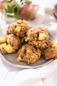 Freshly baked apple oatmeal with apple chunks cookies on small plate.