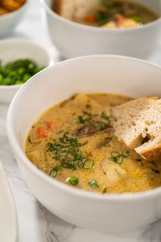 Serving creamy wild mushroom soup made out of dehydrated wild mushrooms in white bowls with sourdough bread.