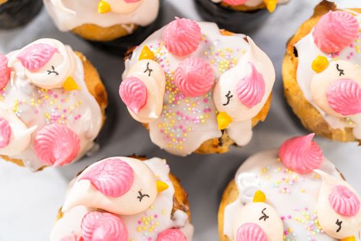 Freshly baked mini Easter bread kulich with lemon glaze, decorated with sprinkles and meringue bird-shaped cookies.