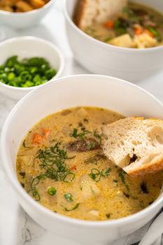 Serving creamy wild mushroom soup made out of dehydrated wild mushrooms in white bowls with sourdough bread.