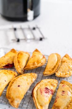 Freshly baked sweet cherry empanadas in the air fryer on the kitchen counter.