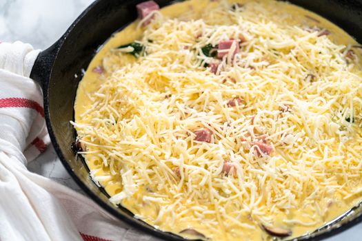 Preparing spinach and ham frittata in cast iron skillet.