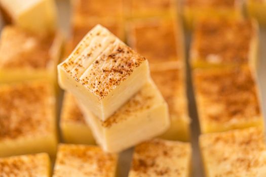 Homemade eggnog fudge pieces on a white cutting board.