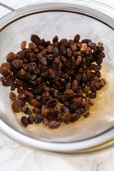 Soaking dried raisins in hot water to baking mini Easter bread kulich.