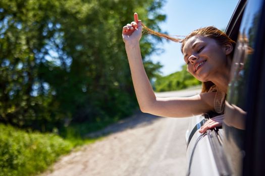 joyful woman rides in a car pulling her head out of the window on a journey. High quality photo