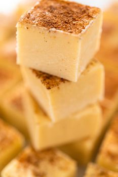 Homemade eggnog fudge pieces on a white cutting board.