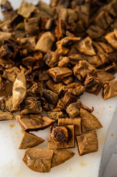 Cutting dehydrated wild mushrooms on a white cutting board.
