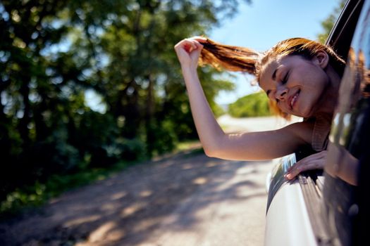 joyful woman rides in a car pulling her head out of the window on a journey. High quality photo