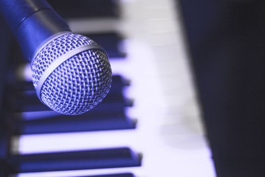 Microphone over piano keys in dim light. No people