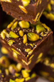 Homemade chocolate pistachio fudge square pieces on a white plate.