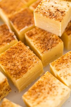 Homemade eggnog fudge pieces on a white cutting board.