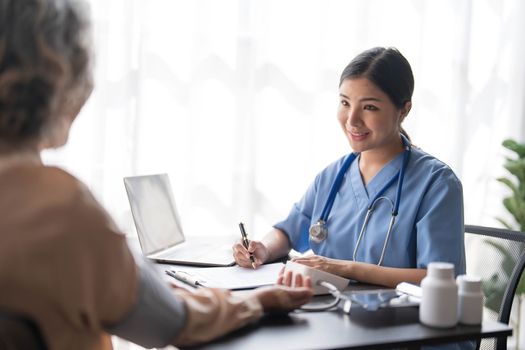 Nurse measuring blood pressure of senior woman patient in retirement home. Home caregiver doing routine checkup of a mature female patient...