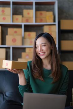 Portrait of Asian young woman SME working with a box at home. small business owner entrepreneur SME and delivery concept.