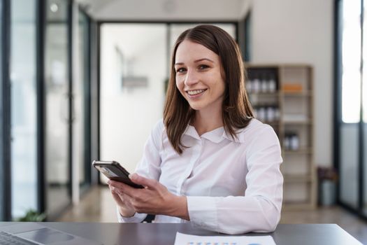 Smiling asian business woman with smartphone in office. Woman in casual at office.