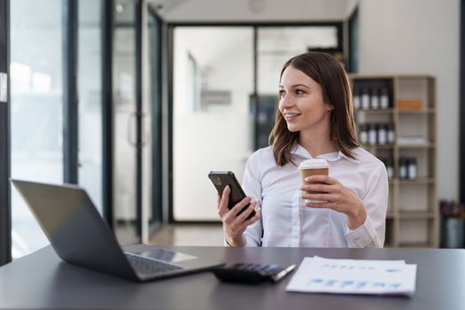 Smiling asian business woman with smartphone in office. Woman in casual at office.