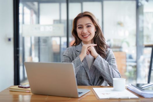 Portrait of Smiling asian business woman with laptop computer in office. Woman in suit at office.