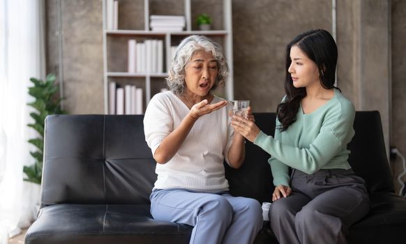 Young Asian woman taking care and giving a glass of water and taken daily medicine or vitamin supplements, elderly healthcare and grandmother...