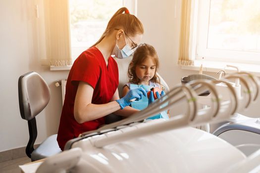 Oral hygiene lesson of jaw anatomical model for child in dentistry. Dentist shows child how to properly brush his teeth with a toothbrush