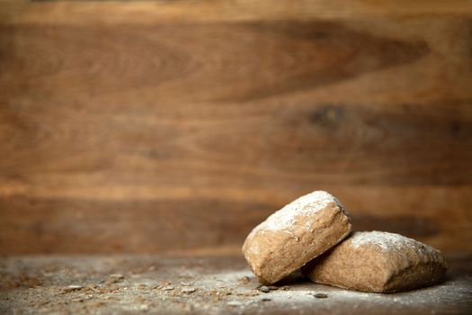 Fresh baked bread with flour on wooden table and background with copy space close up