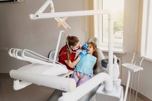 Pediatric dentist examines and consults kid patient in dentistry. Professional hygiene for teeth of child in dentistry. Professional teeth cleaning for child girl