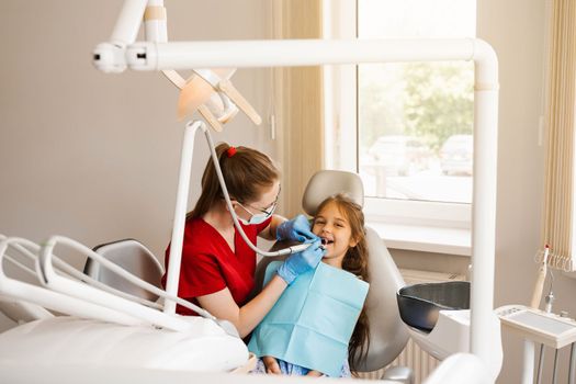 Pediatric dentist examines and consults kid patient in dentistry. Professional hygiene for teeth of child in dentistry. Professional teeth cleaning for child girl