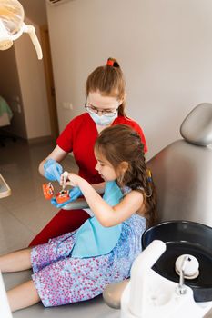 Dentist shows child how to properly use toothbrush for brush teeth. Jaw anatomical model teeth brushing. Pediatric dentist teaching oral hygiene lesson for kids in dentistry